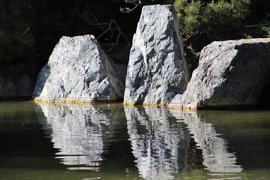 Large gray rocks in calm water with reflections