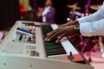 Close-up of hands playing a vintage synthesizer on stage