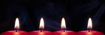 Four lit red candles with smoke against dark background