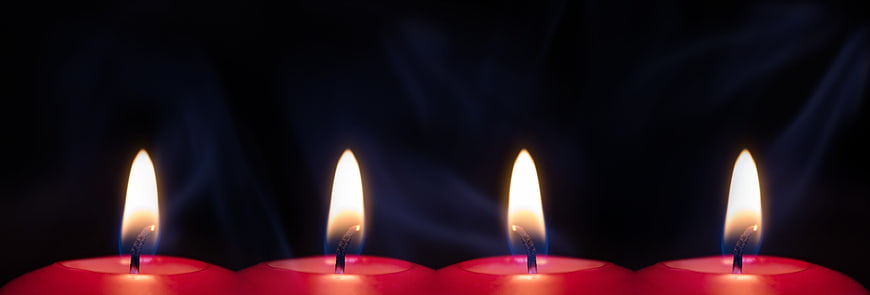 Four lit red candles with smoke against dark background