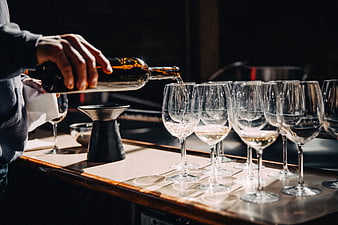 Bartender Pouring White Wine into Glasses at Bar