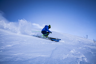 Skier carving through fresh powder on a sunny winter slope