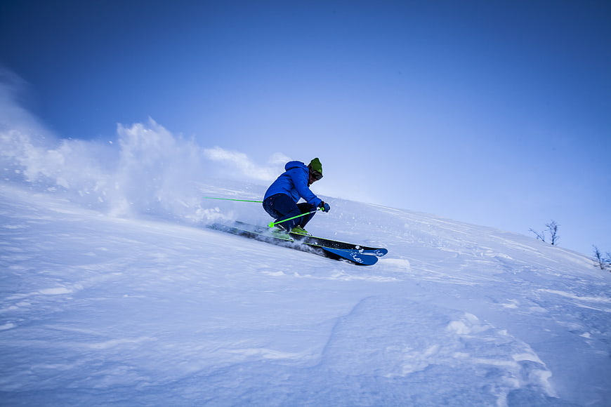 Skier carving through fresh powder on a sunny winter slope