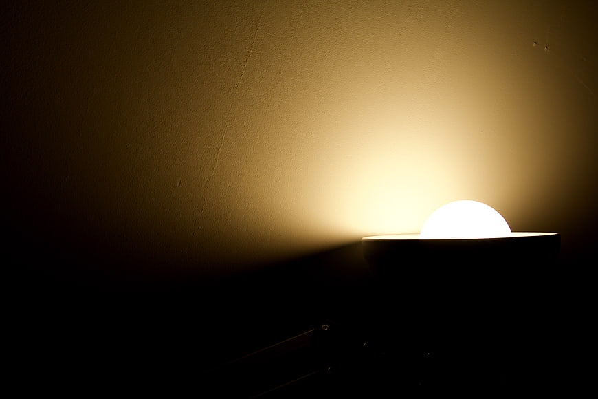 Minimalist wall sconce casting warm light on textured wall