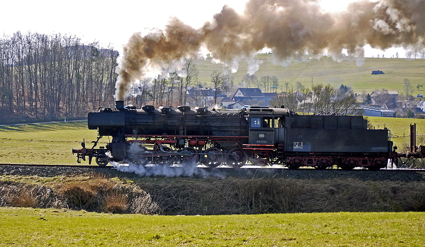 Vintage Steam Locomotive Emitting Smoke on Rural Railway Track