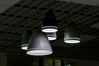 Modern pendant lights hanging from industrial ceiling grid
