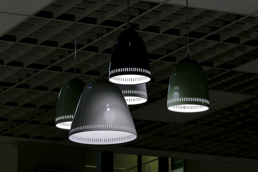 Modern pendant lights hanging from industrial ceiling grid