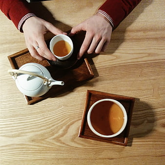 Top view of hands holding tea cup on wooden table