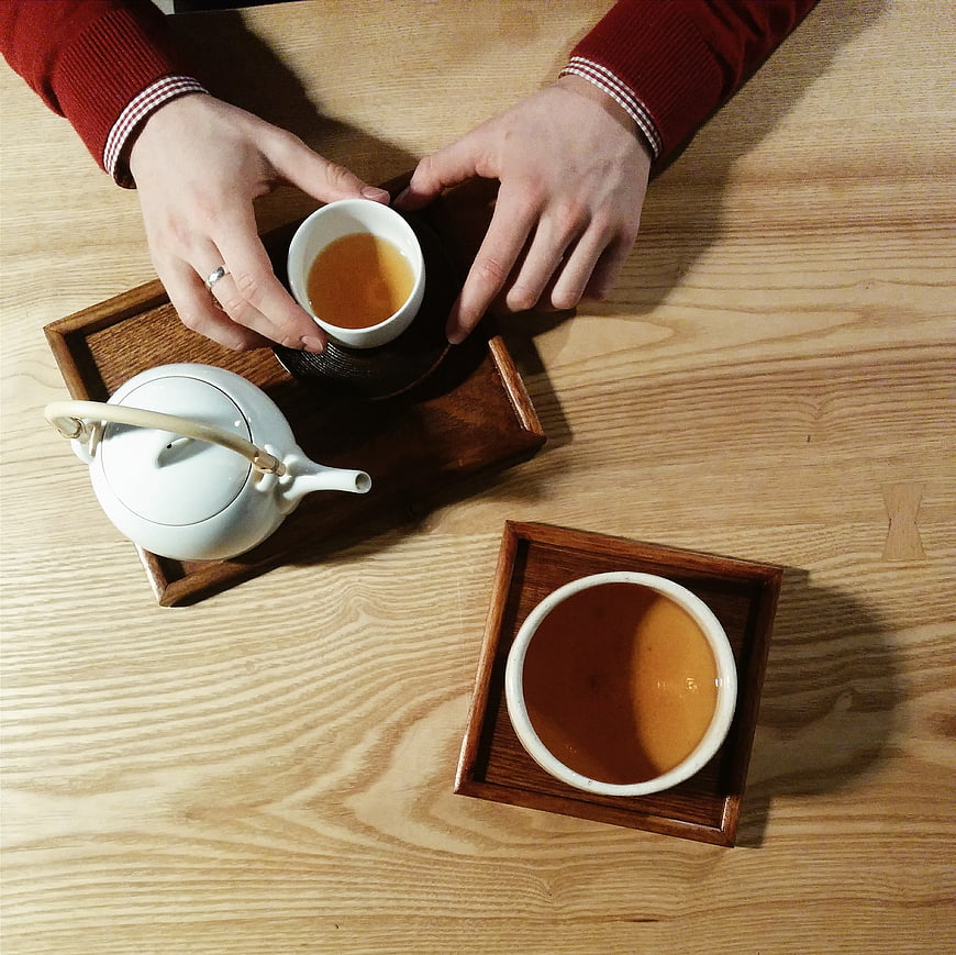 Top view of hands holding tea cup on wooden table