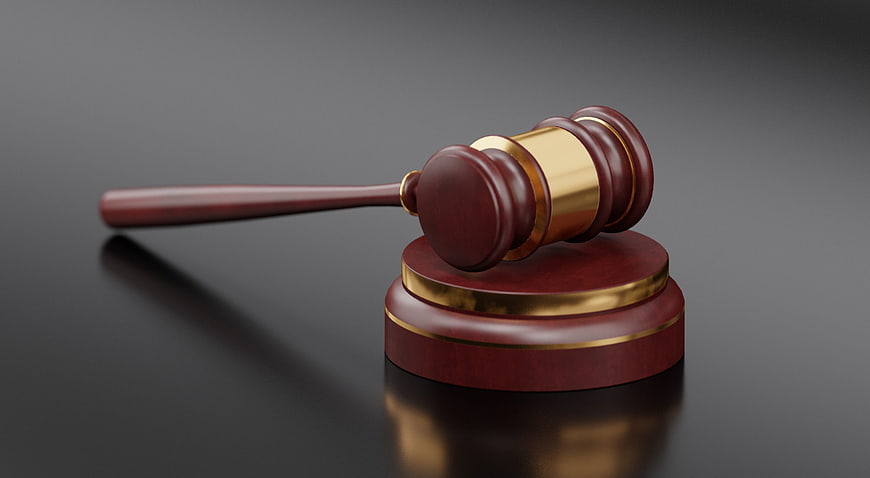 Wooden judge gavel with gold accents on dark reflective surface