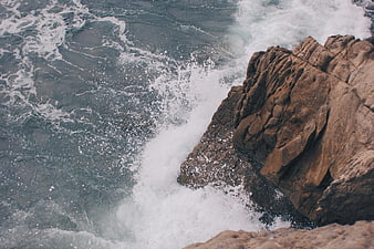 Aerial view of ocean waves crashing against rugged coastal cliffs