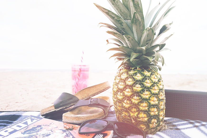 Tropical beach vacation flat lay with pineapple and sunglasses