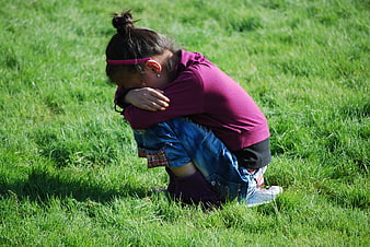 Sad young girl crying alone on green grass