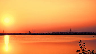 Vibrant Orange Sunset Over Calm Lake with Silhouette