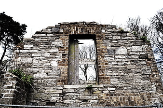 Weathered stone ruins with empty window frame and overgrown vegetation