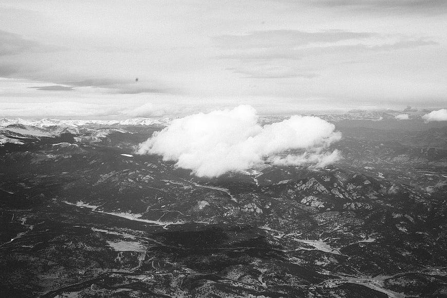 Aerial black and white view of mountain range with clouds
