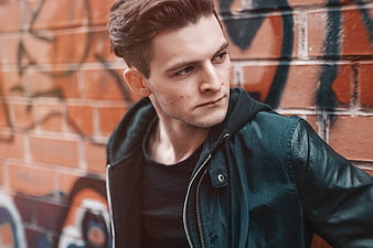 Stylish Young Man in Green Jacket Against Graffiti Wall