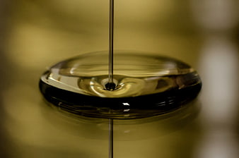 Macro shot of golden oil being poured onto a reflective surface