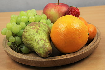 Fresh mixed fruit bowl with grapes, pear, orange, apple, and strawberry