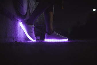 White sneakers with glowing purple LED soles at night
