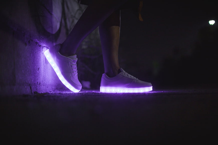 White sneakers with glowing purple LED soles at night