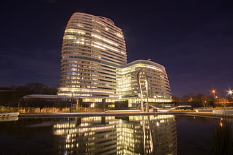 Modern Curved Office Building at Night with Water Reflection