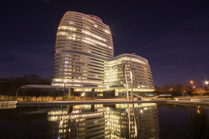 Modern Curved Office Building at Night with Water Reflection