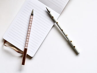 Minimalist white notebook and gold pens on white background