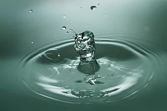 High-speed water droplet splash with ripples on teal background