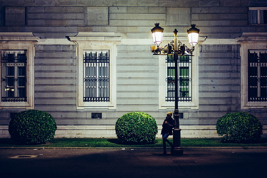 Woman leaning on vintage street lamp at night