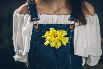 Woman in denim overalls with yellow flower in pocket