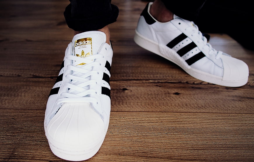 White Adidas Superstar Sneakers on Wooden Floor