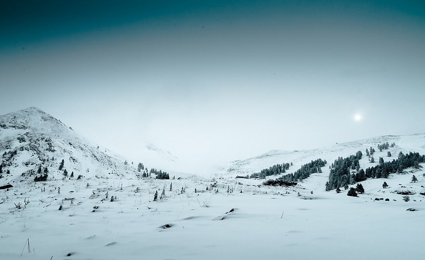 Serene Snowy Mountain Landscape with Pine Trees and Blue Sky