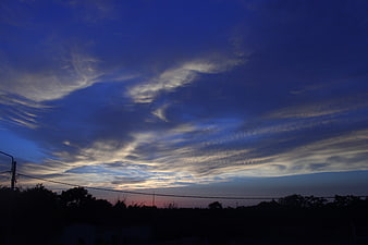 Dramatic blue twilight sky with wispy clouds over dark silhouette