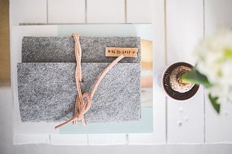 Grey felt to-do list notebook on white desk with flower