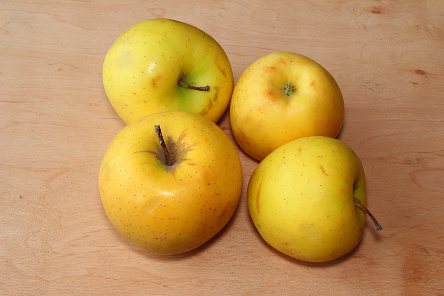 Fresh yellow apples on a light wooden table background