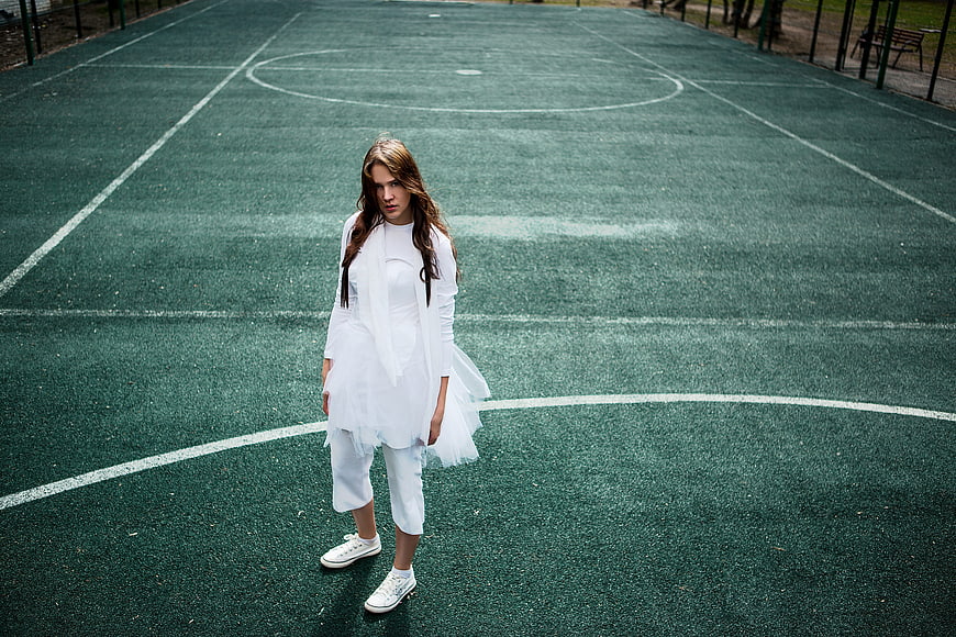Woman in White Outfit Standing on Green Tennis Court
