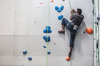 Man Rock Climbing on Indoor Wall with Blue Holds