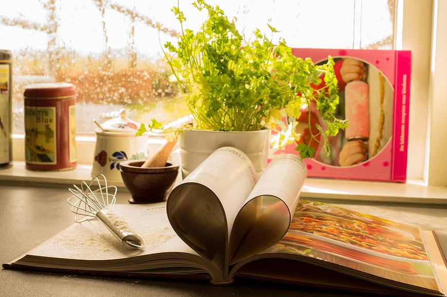 Open Cookbook with Heart Shape and Fresh Herbs on Kitchen Counter