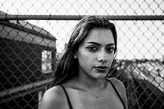 Black and white portrait of a woman in front of a chain-link fence