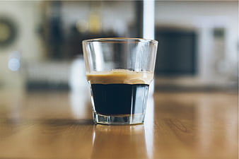 Close-up of espresso shot in glass on wooden table