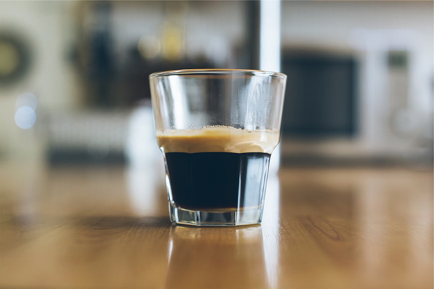 Close-up of espresso shot in glass on wooden table