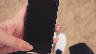Hand holding smartphone with blank screen on sandy background