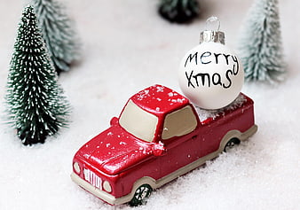 Red Toy Pickup Truck Carrying Merry Christmas Ornament in Snow