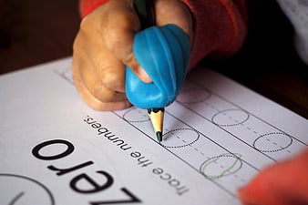Child Hand Using Blue Pencil Grip on Kindergarten Number Worksheet