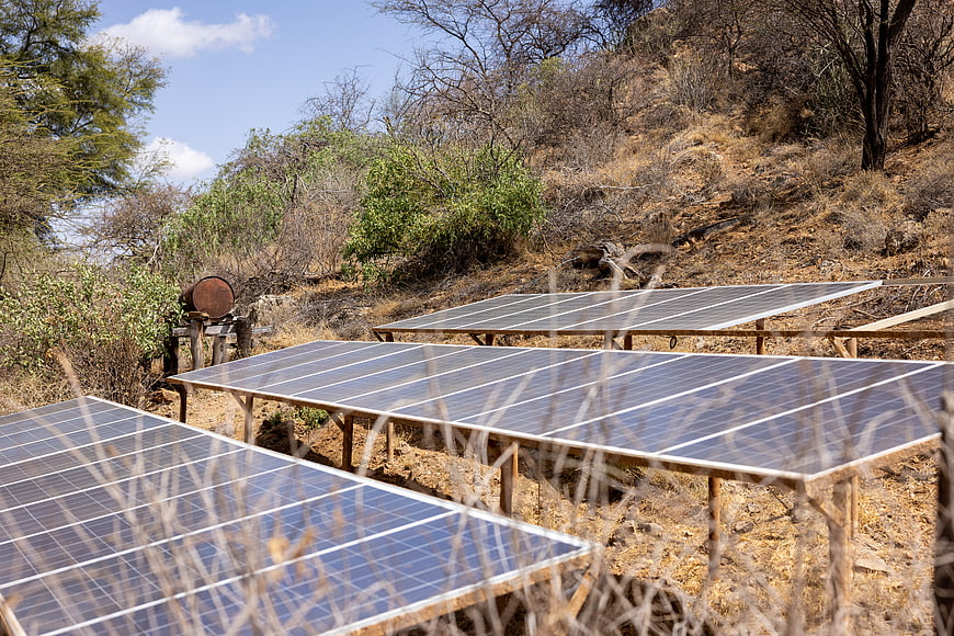 Solar panels installed on a dry hillside with blue sky