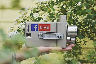 Hand holding vintage camera with Facebook Live sticker