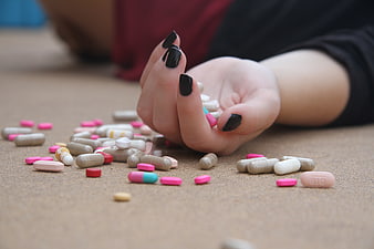Woman's Hand Reaching for Scattered Pills on Floor