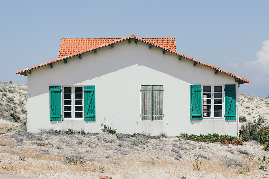 White House with Green Shutters in Sandy Landscape