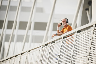 Happy Senior Man Listening to Music on Modern Bridge
